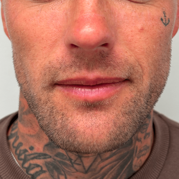 Man with tattoos and anchor tattoo above his left eyebrow, close-up