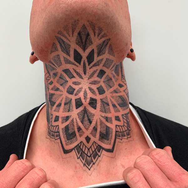 Man's neck showing large mandala tattoo, intricate and detailed