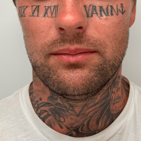 Man with neck tattoos including "VAM" and "XI VII XI" on his forehead
